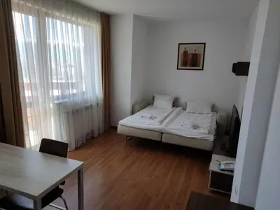 a room with a bed and a table and a window at Belvedere Holiday Club ,apartment A202 in Bansko