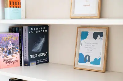 a shelf with books and a framed picture at Perfect Long-term Stay Stylish and Spacious Top Center Next to Vitosha Blvd in Sofia