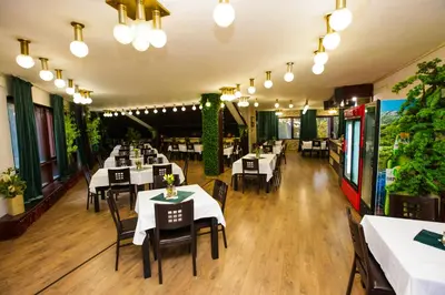 a restaurant with white tables and chairs and plants at Почивна станция - ТЕЦ Бобов дол in Bistriza