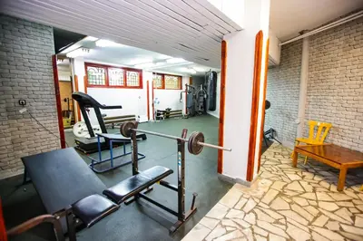 a fitness room with a gym with a bench and weights at Почивна станция - ТЕЦ Бобов дол in Bistriza