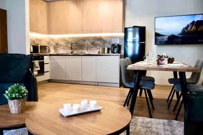 a living room with a table and a kitchen at Antonovi Apartments Deluxe in hotel Laplandia in Pamporovo