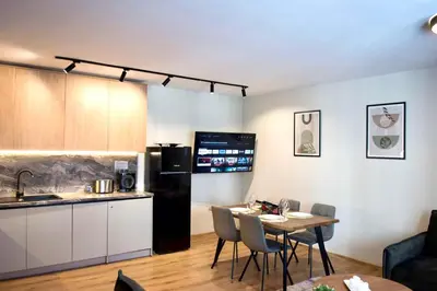 a kitchen and living room with a table and a refrigerator at Antonovi Apartments Deluxe in hotel Laplandia in Pamporovo