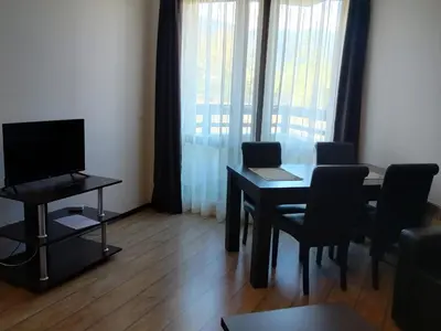 a small living room with a table and a television at Alpine Lodge Bansko Apartments in Bansko