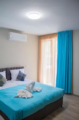 a bedroom with a bed with blue sheets and a window at Guesthouse The Rock in Sapareva Banya