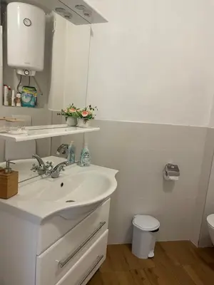 a white bathroom with a sink and a toilet at апартамент Римската стена in Hisarya