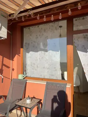 a patio with two chairs and a table in front of a window at апартамент Римската стена in Hisarya