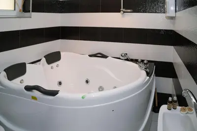 a white bath tub in a black and white bathroom at Къща за гости Донука in Panichishte
