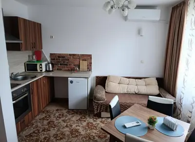 a small kitchen and a living room with a table at Flat Cedar Lodge 2min walk to gondola in Bansko