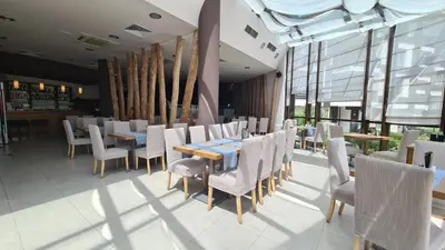 a restaurant with white chairs and tables and windows at Studio Maria in Bansko