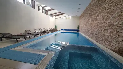 a large swimming pool with chairs and a brick wall at Studio Maria in Bansko
