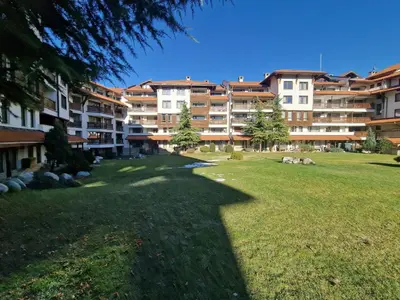 a large apartment building in a park with a grass field at Bansko Royal Towers George Apartment, next to the Gongola in Bansko