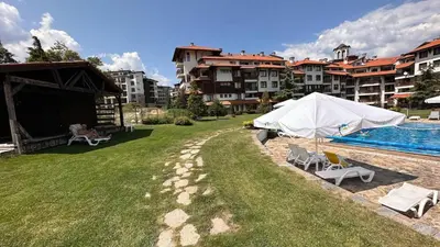 a yard with a swimming pool and a white umbrella at Bansko Royal Towers George Apartment, next to the Gongola in Bansko