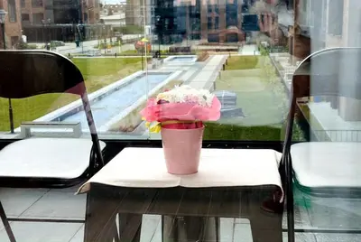 a cup of flowers sitting on a table with a window at Мoka Apartment in Sofia