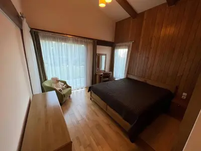 a man sitting in a chair in a bedroom at Villa - VALL DI VALL in Pirin Golf & Country Club in Razlog