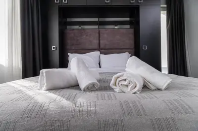 a bed with white pillows and towels on it at Chic 1BR Apartment with Balcony in Plovdiv in Plovdiv