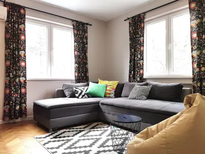 a living room with a couch and two windows at Beautifully Decorated Functional Apartment in Sofia