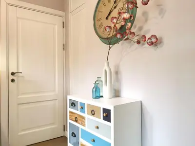 a vase on a dresser with a clock on the wall at Beautifully Decorated Functional Apartment in Sofia