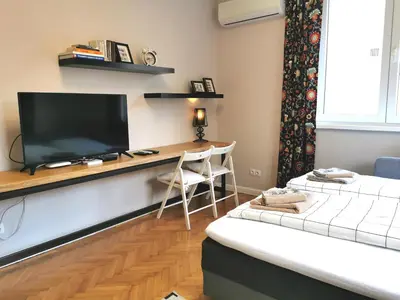 a room with a desk with a television and a bed at Beautifully Decorated Functional Apartment in Sofia