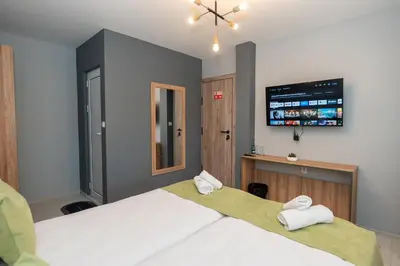 a bedroom with two beds and a flat screen tv at Къща за гости Оскови in Velingrad