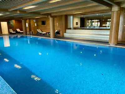 a large blue swimming pool in a building at Spacious penthouse chalet apartment in Pirin Golf and Country Club in Razlog