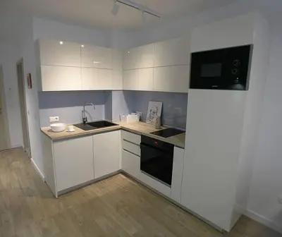 a kitchen with white cabinets and a black appliance at Modern Turquoise Apartment/free WiFi in Sofia