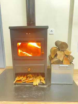 a woodburning stove with logs in a room at Апартамент за гости Байрактарова in Smolyan