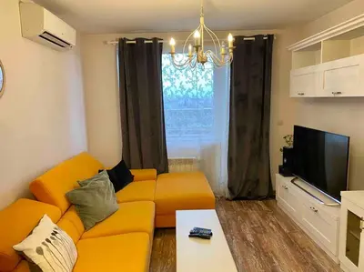 a living room with an orange couch and a television at Stylish Magenta Apartment - terrace & free parking in Sofia
