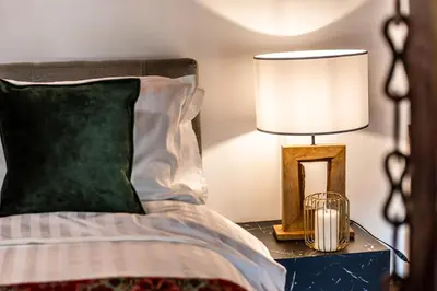 a bed with a green pillow and a lamp on a table at Slona, Heritage Home in Old Town Plovdiv in Plovdiv