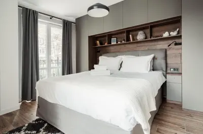 a bedroom with a large white bed with a wooden headboard at 8th Hill Apartments in Plovdiv