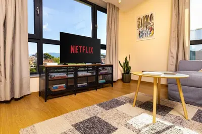 a living room with a tv and a table at Hills View Central Apartment in Plovdiv