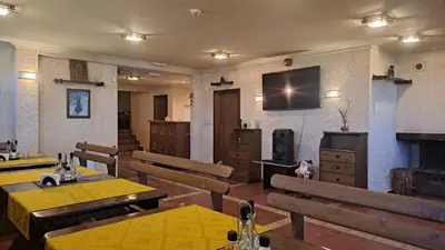 a room with tables and chairs and a television on the wall at REAL Guest House in Bansko