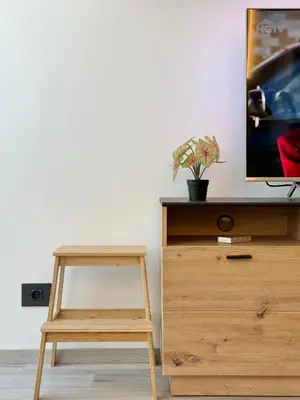 a tv on top of a wooden dresser with a wooden stool at City Modern & Classy Apartment for 4 Guests & Parking in Sofia
