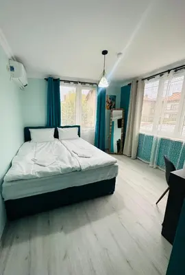a bedroom with a large bed in a room with blue curtains at VELI HOUSE VELINGRAD/ ВелиХаус Къща за гости Велинград in Velingrad
