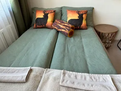 a bed with a green comforter with two deer pillows at Borovets Gardens Funky Fresh Studio by Joro in Borovets