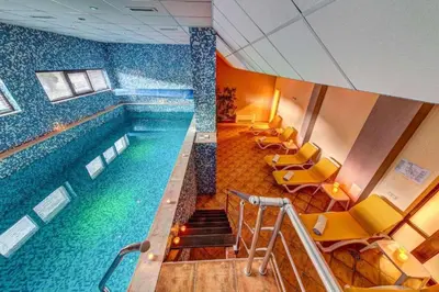 a large swimming pool in a building with yellow chairs at N.Joy Holiday Apartment 534 by Oak Residence in Smolyan