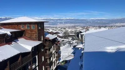 a city with snow covered roofs and buildings at Ski view suite Emerald Bansko in Bansko
