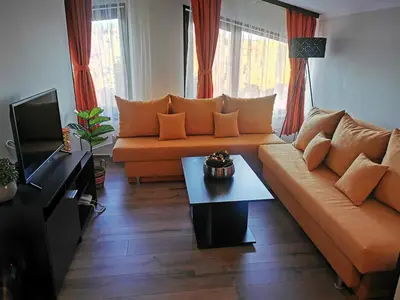 a living room with an orange couch and a table at Private Apartments in Hotel Snezhanka in Pamporovo