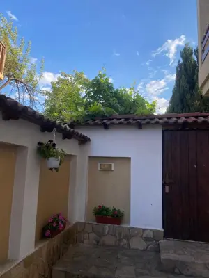 a white house with a wooden door and flowers at Deers in Bansko