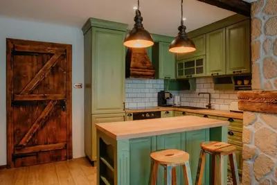 a kitchen with green cabinets and a wooden door at The Owl's Nest 2 in Velingrad