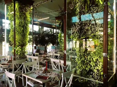 a restaurant with tables and chairs and plants on the wall at Harmony apartment in Sofia