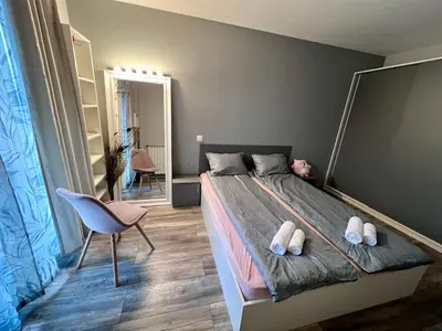 a bedroom with a bed and a chair and a mirror at Harmony apartment in Sofia