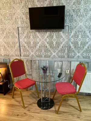 two chairs and a glass table with a tv on a wall at Polaris Inn Apartments in Bansko