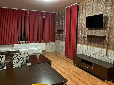 a living room with red curtains and a tv at Polaris Inn Apartments in Bansko