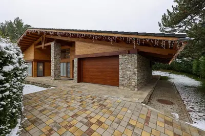 a house with a wooden garage with a roof at Villa Katerina Deluxe w Sauna - Pirin Golf and Country Club in Bansko