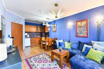 a living room with a blue couch and a kitchen at Cedar Lodge III One BDRM Flat B2 in Bansko