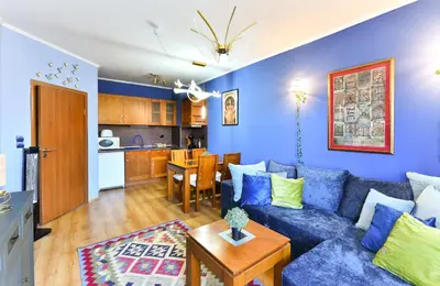 a living room with a blue couch and a kitchen at Cedar Lodge III One BDRM Flat B2 in Bansko