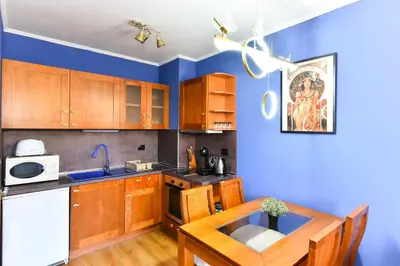 a kitchen with wooden cabinets and a blue wall at Cedar Lodge III One BDRM Flat B2 in Bansko
