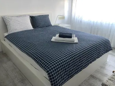 a bedroom with a bed with a blue and white checked blanket at Cozy and modern apartment Krasno selo, free parking in Sofia