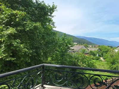 a balcony with a black railing and trees and mountains at Danaya in Petrich