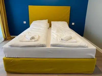 a yellow bed with two white pillows on it at Boutique Magenta Pearl Apartment with free WiFi in Sofia